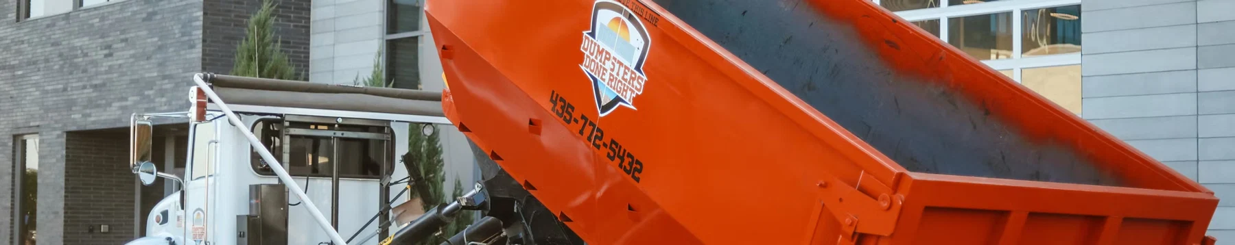 Dumpsters Done Right orange dumpster being delivered by a company truck